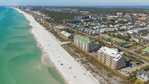 An aerial view of a coastal area with a beach, buildings, and a road. - Caribbean Dunes by Panhandle Getaways (Destin)
