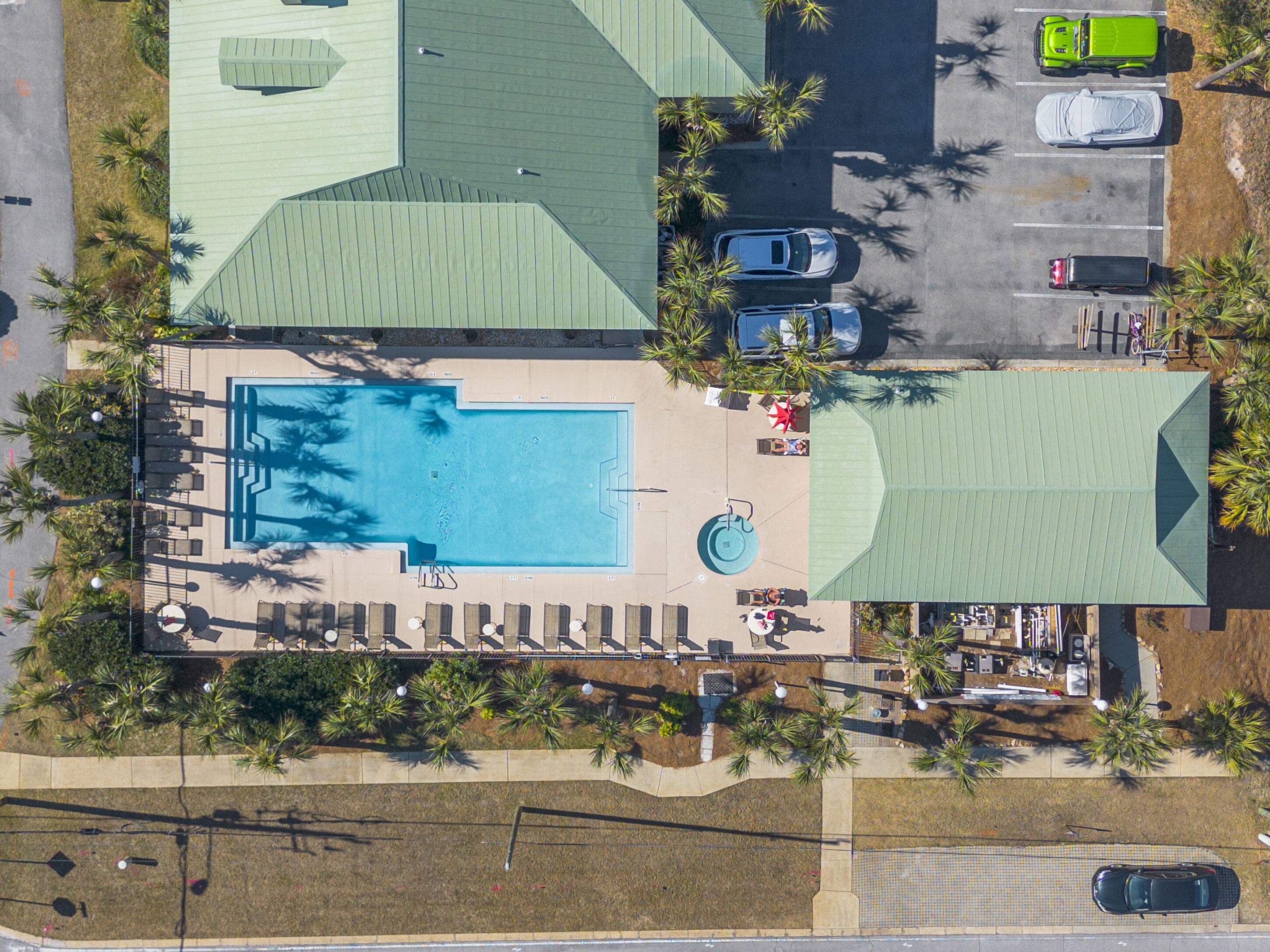 Vue aérienne d’un hôtel avec une piscine, des chaises longues et des palmiers.