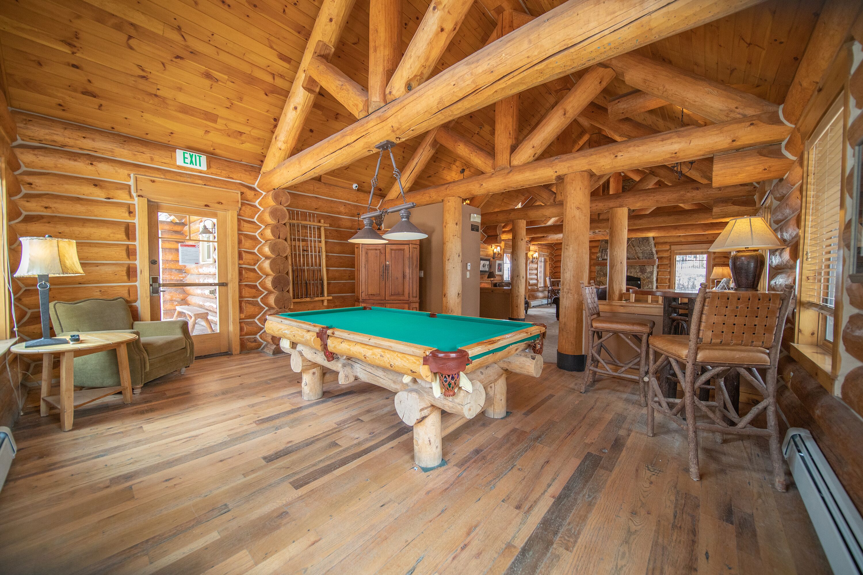 Un interno in legno con tavolo da biliardo, poltrone e camino.