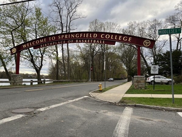 Un letrero de bienvenida en el Springfield College, con una calle despejada y un hidrante.