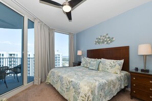 Relax in comfort with a large bed, wooden headboard, and city views through a sliding glass door.