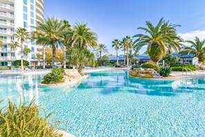 Relax by the resort pool surrounded by palm trees and a building with balconies.