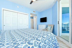 Une chambre dotée d’un grand lit, d’un téléviseur à écran plat, d’un ventilateur de plafond et offrant une vue sur la ville grâce à une porte-fenêtre coulissante.
