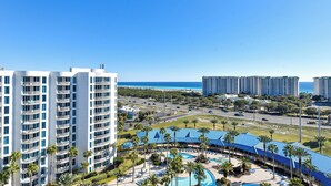 A high-rise hotel with multiple balconies, a swimming pool area with sun loungers, and a view of the ocean. - Cozy condo w/ Vibrant Amenities & Zero-Entry Lagoon Pool (Destin)