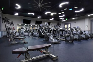 Une salle de sport équipée de divers appareils d’exercice, notamment des tapis de course, des vélos d’appartement et des appareils de musculation.