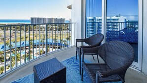 A balcony with wicker furniture, a view of a beach, and a pool area. - Cozy condo w/ Vibrant Amenities & Zero-Entry Lagoon Pool (Destin)