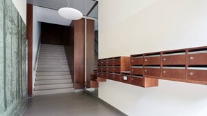 Un interior moderno con una escalera, un mueble de almacenamiento de madera fijado a la pared y una lámpara colgante.