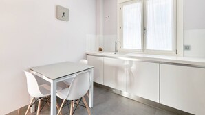 Una cocina moderna con armarios blancos, encimera blanca y una ventana con cortinas.
