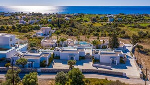 A coastal residential area with modern white buildings, a clear view of the sea, and a well-maintained landscape.