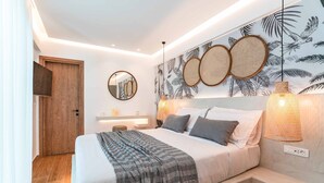A modern bedroom with a large bed, a wooden door, a wall-mounted mirror, and a tropical-themed wall decoration.