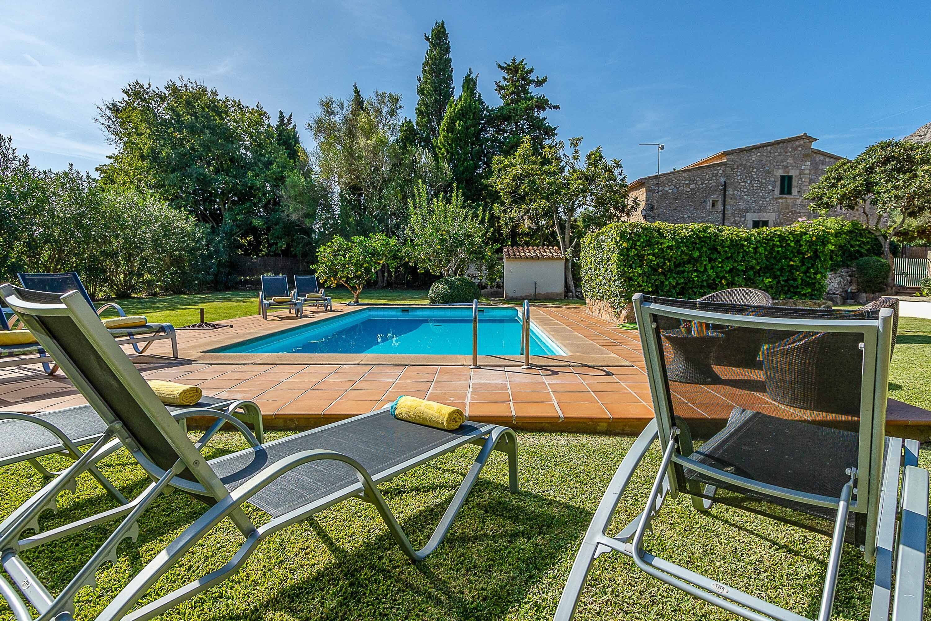A backyard with a swimming pool, lounge chairs, and a small building.