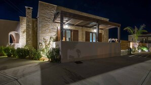 Una casa moderna con fachada de piedra, un porche cubierto y un camino de acceso bien iluminado.