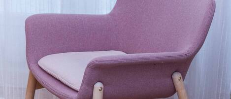 Un fauteuil violet avec des pieds en bois et un coussin.