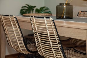 A dining area with a wooden table and woven chairs. - Pagrati Urban Oasis Getaway 2Bd Apt (Athens)