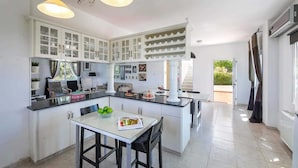 A modern kitchen with white cabinets, a dining area with a table and chairs, and pendant lighting. - Pine Retreat - Four Bedroom Villa, Sleeps 8 (Argaka)