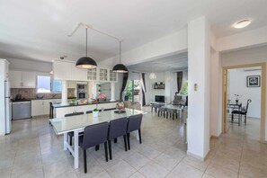 A modern kitchen with white cabinets, a central island, and pendant lighting.