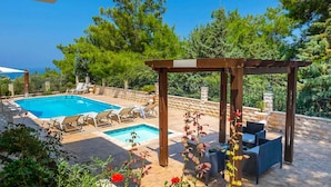 A poolside area with a pergola, lounge chairs, and a small table. - Pine Retreat - Four Bedroom Villa, Sleeps 8 (Argaka)