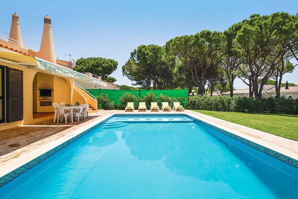 Relax by the serene pool surrounded by lush greenery and comfortable lounge chairs.