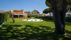 Une propriété résidentielle dotée d’une pelouse bien entretenue, d’un jardin circulaire et d’un grand arbre.