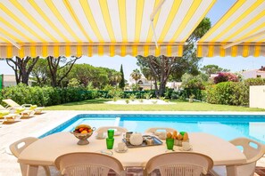 Relax by the pool surrounded by lush greenery and enjoy a meal at the outdoor dining area.