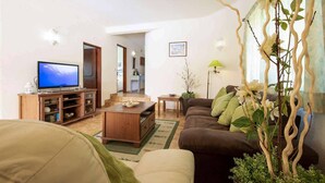 Un salon avec un téléviseur, un meuble de rangement en bois, un canapé marron et une plante.