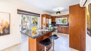 A modern kitchen with wooden cabinets, a granite countertop, and a built-in island with bar stools.