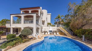 A two-story house with a swimming pool, a covered patio, and a staircase leading to the upper level.