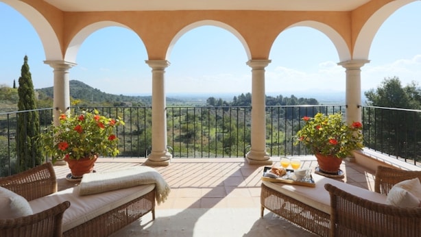A covered terrace with wicker furniture, potted plants, and a scenic view. - Residencia Baranda by Vida Villas (Alaró)