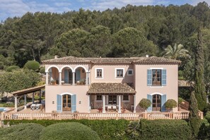Una villa de estilo mediterráneo de dos plantas, con techo de tejas, ventanas arqueadas y un balcón.