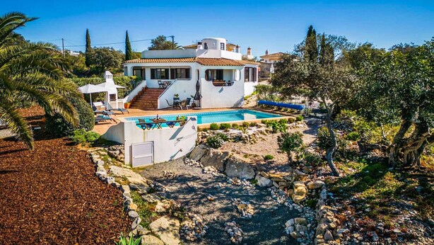 A house with a swimming pool, outdoor seating, and a garden.