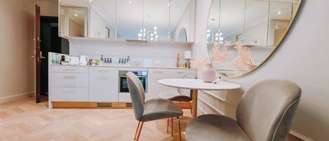 A modern kitchen with white cabinets, a round dining table, and two grey upholstered chairs.