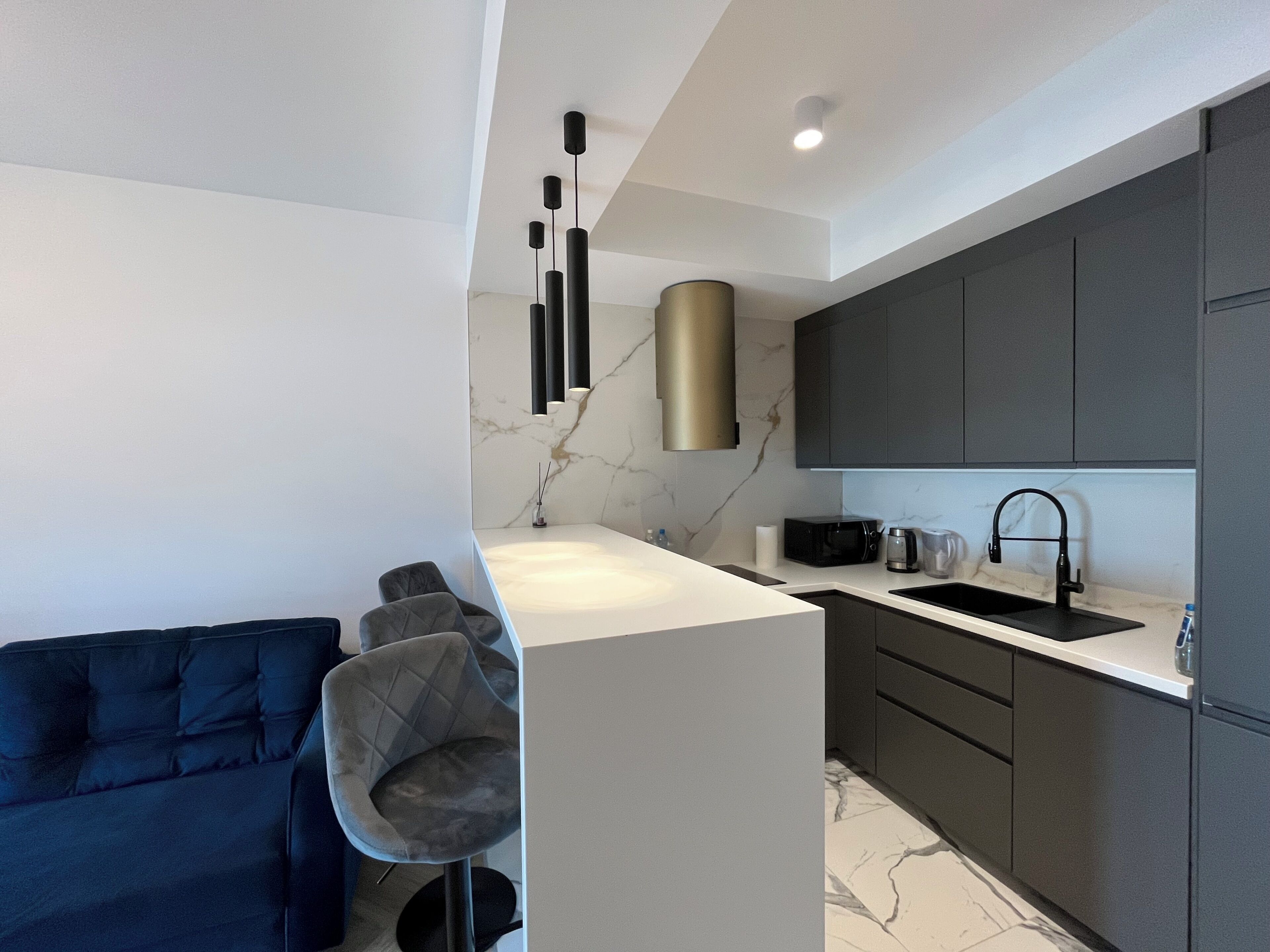 A modern kitchen with a marble backsplash, dark cabinetry, and a central island with seating.