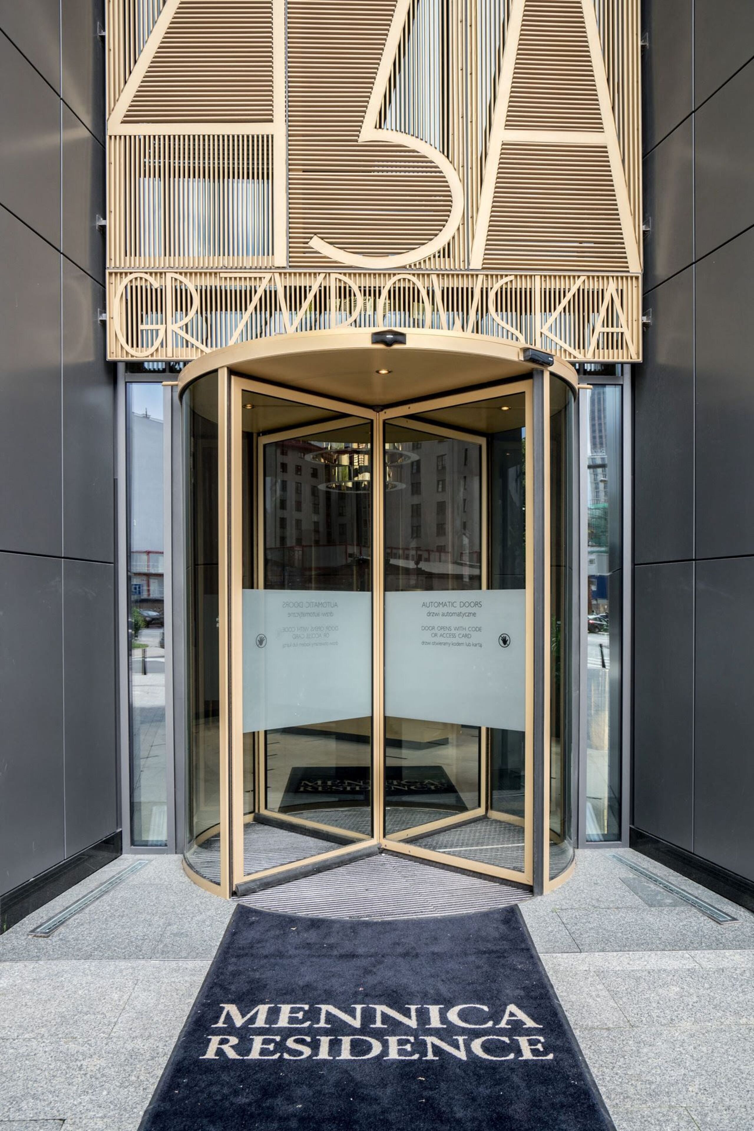 Une porte tournante avec une pancarte indiquant « Portes automatiques » et « La porte s’ouvre avec un code ».