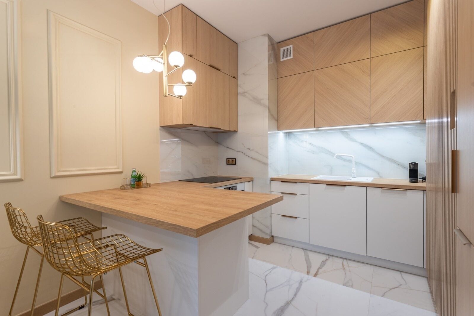A modern kitchen with a wooden island, bar stools, and a built-in stove.