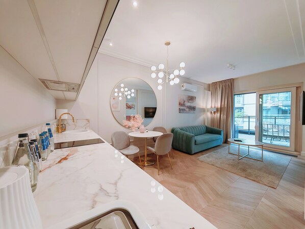 A modern hotel room with a marble vanity, round mirror with lights, a green sofa, and a balcony with a view. - Vip Warsaw Apartments (Warsaw)