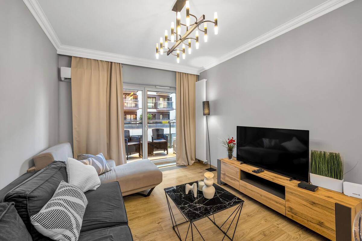 A modern living room with a sofa, TV, and a wooden entertainment unit.