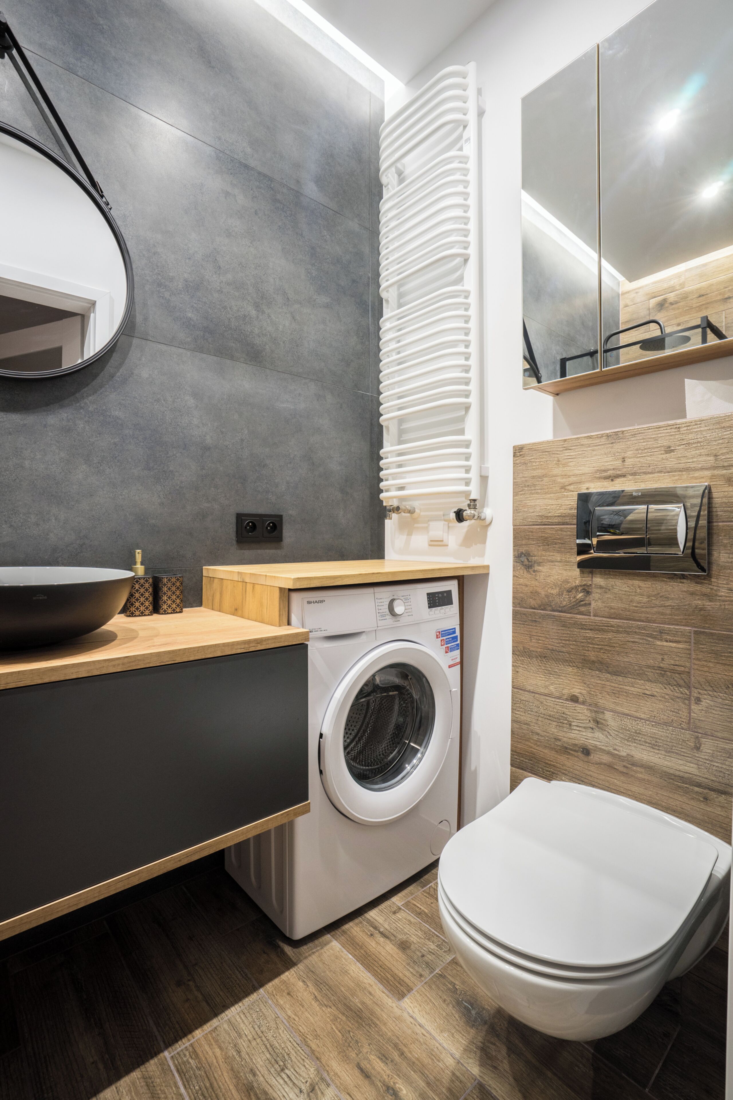 Uma casa de banho moderna com lavatório, máquina de lavar e sanita.
