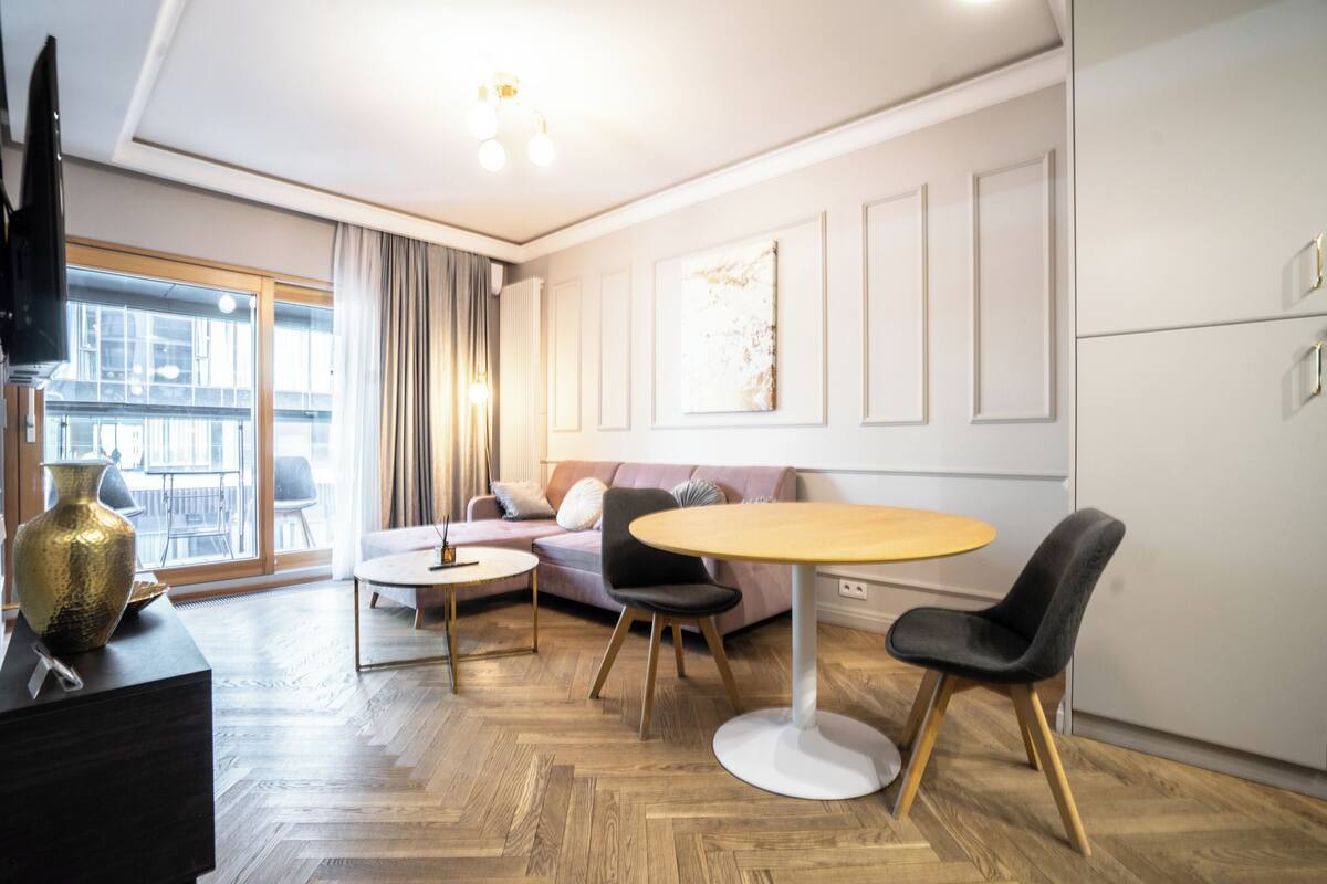 A modern living room with a sofa, round table, and chairs.
