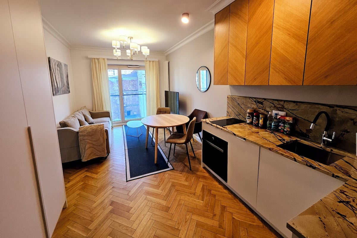 A compact living space with a kitchenette, dining area, and a sofa set.