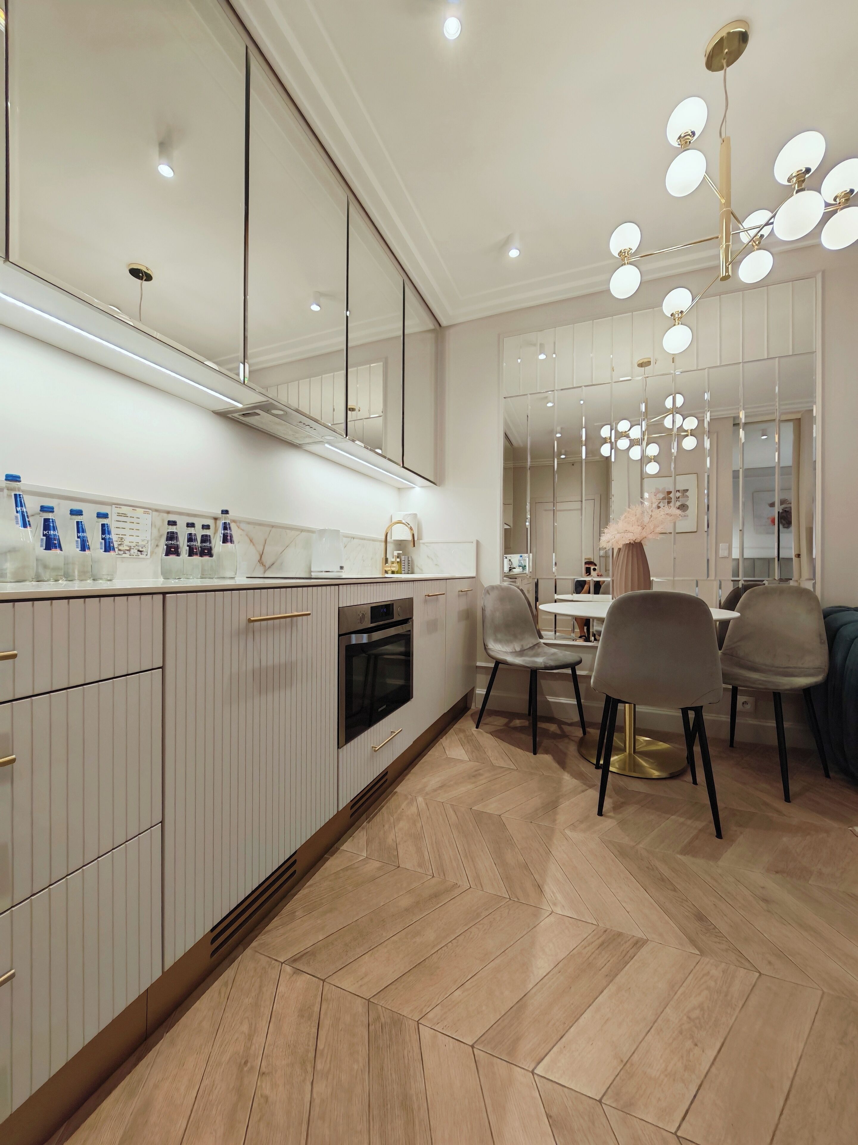 Een moderne keuken met een centraal eiland, een inbouwoven en een eetgedeelte met stoelen en een tafel.