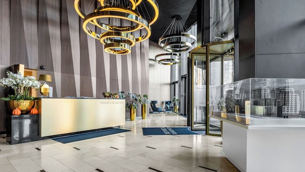 A modern reception area with a reception desk, decorative plants, and a cityscape model. - Vip Warsaw Apartments (Warsaw)