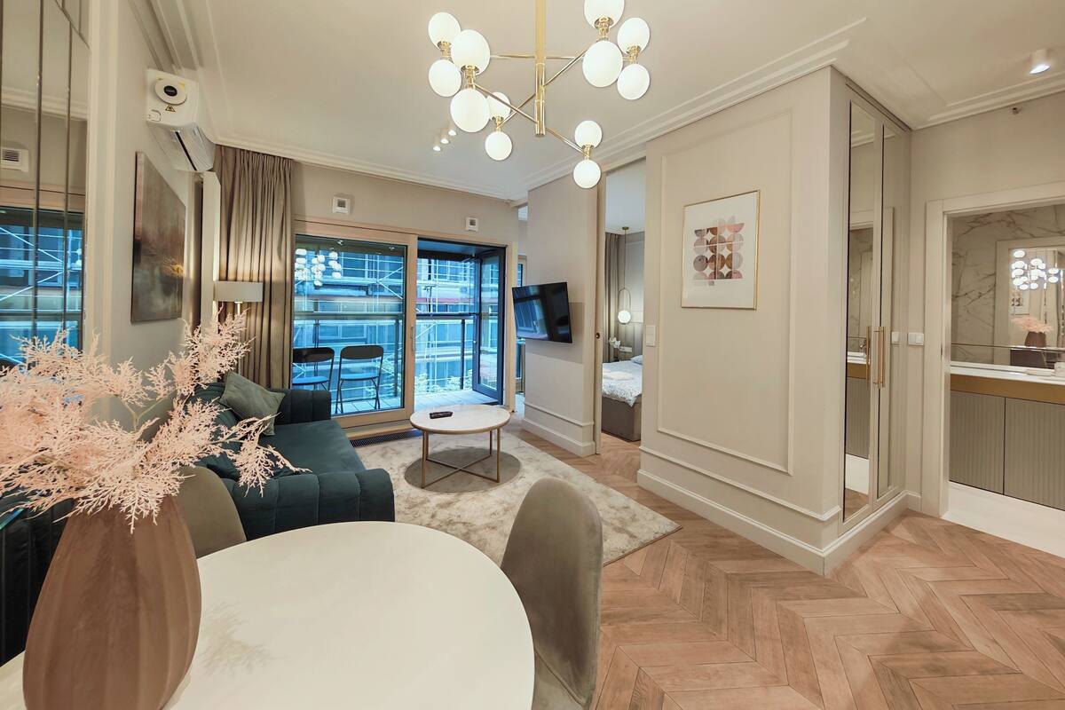 A modern living room with a sofa, a round table, and a chandelier.