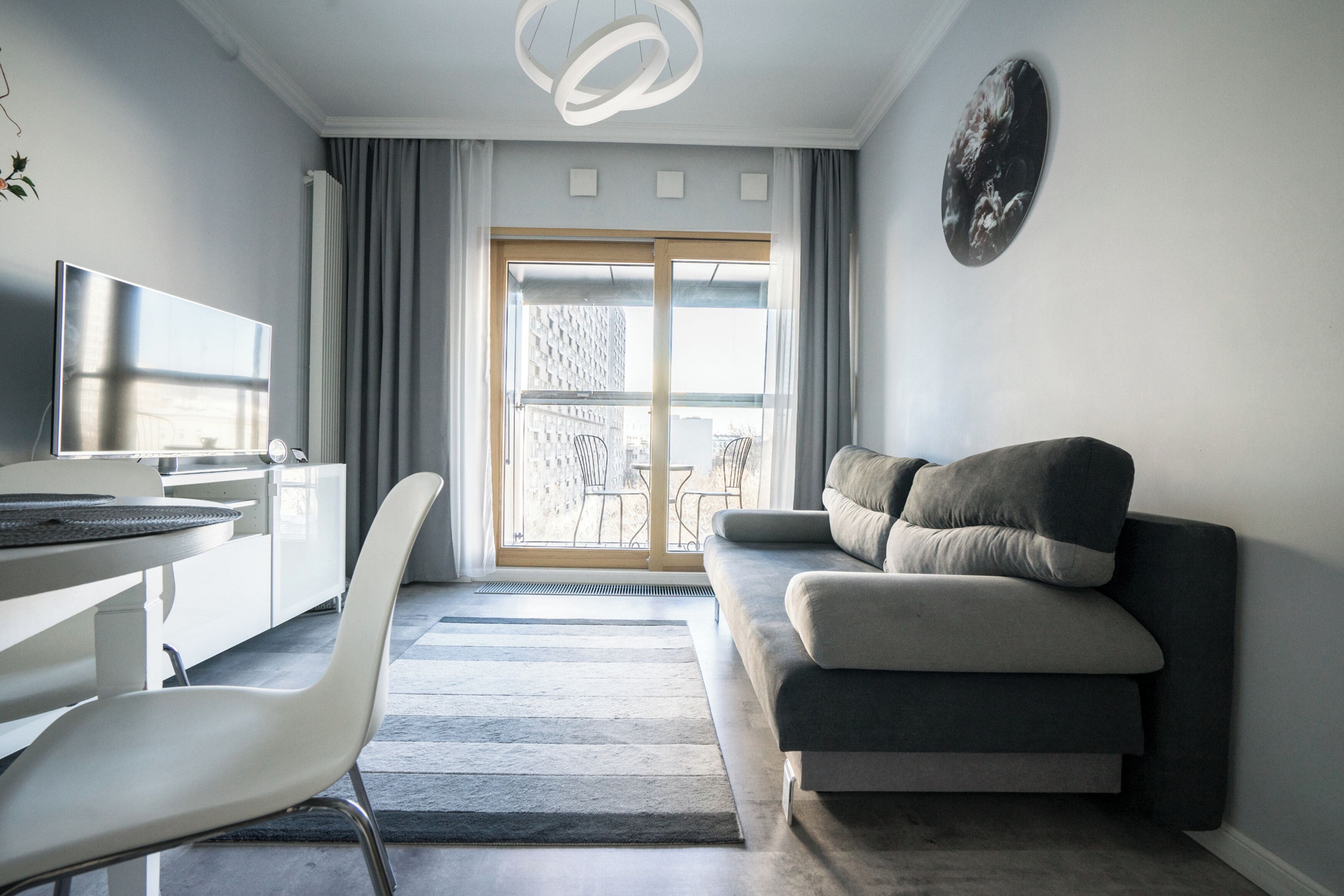 A modern living room with a sofa, a TV, and a dining area with a table and chairs.