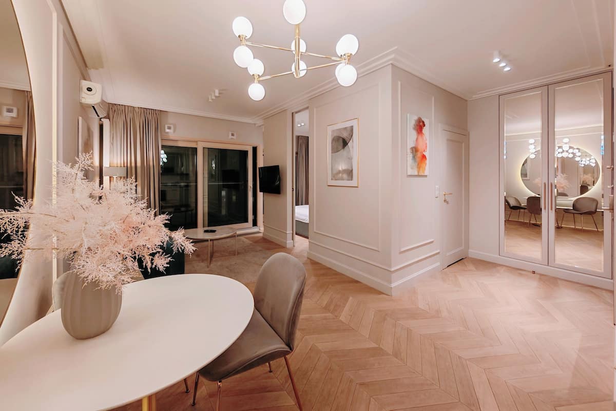 A modern interior with a dining area, a chandelier, and a large sliding glass door leading to a balcony.
