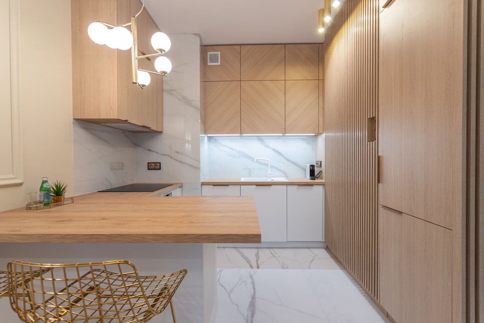 Une cuisine moderne avec des meubles en bois, un pare-feu en marbre et un plan de travail en bois.