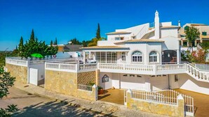 A white villa with a large patio, multiple balconies, and a stone wall. - Casa Oliveira - Four Bedroom Villa, Sleeps 8 (Albufeira)