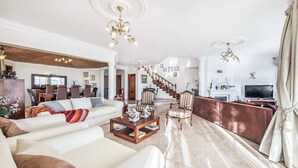 A spacious living room with a large sofa set, a coffee table, and a fireplace. There is a staircase leading to an upper level. - Casa Oliveira - Four Bedroom Villa, Sleeps 8 (Albufeira)