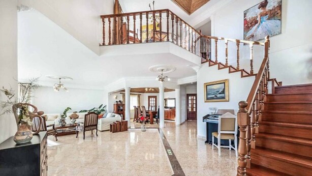 A spacious lobby with a marble floor, a wooden staircase, and a mezzanine level. - Casa Oliveira - Four Bedroom Villa, Sleeps 8 (Albufeira)