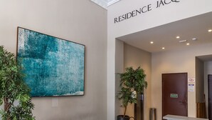 A reception area with a modern design, including a bench, a large abstract painting, and a sign that reads "RESIDENCE JACQUES P."
