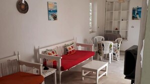 A room with a white sofa, a small table, a TV, and a bookshelf. - Dar Tobbel Borj Errass Mahdia (Mahdia)